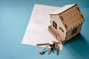 Picture of a small model wooden house with a mortgage and set of keys