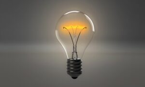 See through light bulb with a yellow light in front of a grey background